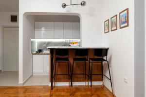 スボティツァにあるAquarelle apartmentの白いキャビネット付きのキッチン、バースツール付きのカウンター