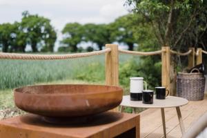 a bowl on a table with two cups on a table at Toad Hall Lodges - Luxury Eco Lodges Near Southwold! in Wangford