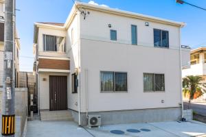 a white house with a door on a street at Y's沖縄リゾートベースNo.2 in Onna