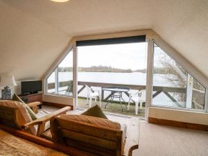 a living room with a large window with a view of the water at Cygnus Boathouse in South Walsham