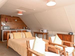 a bedroom with a bed and two chairs and a kitchen at Cygnus Boathouse in South Walsham