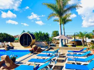 uma fila de espreguiçadeiras azuis ao lado de uma piscina em Macaronesia Love Spa, sauna y piscina em Buzanada