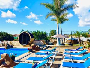 a row of blue lounge chairs next to a swimming pool at Macaronesia Love Spa, sauna y piscina in Buzanada