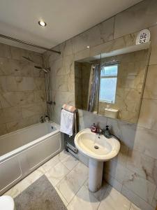 W łazience znajduje się umywalka, lustro i wanna. w obiekcie Luton Town House Near AIRPORT w Luton
