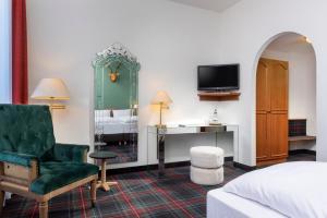 a hotel room with a bed and a chair and a television at Wyndham Garden Donaueschingen in Donaueschingen