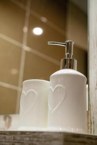 a white soap dispenser sitting on top of a bathroom sink at Gogolapartman Tisza in Szeged