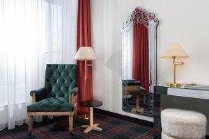a room with a green chair and a mirror at Wyndham Garden Donaueschingen in Donaueschingen