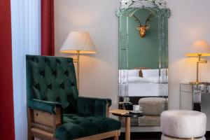a bedroom with a green chair and a mirror at Wyndham Garden Donaueschingen in Donaueschingen