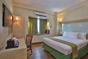 una camera d'albergo con letto, scrivania e TV di Microtel by Wyndham Baguio a Baguio