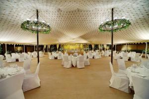 Habitación grande con mesas y sillas blancas y lámparas de araña. en Hyatt Regency Amritsar en Amritsar