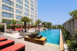 uma piscina com bancos vermelhos e um edifício em Hyatt Regency Amritsar em Amritsar