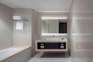 a bathroom with a sink and a tub and a mirror at Hyatt Place Dubai Jumeirah in Dubai