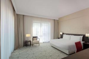a bedroom with a large white bed and a chair at Hyatt Place Dubai Jumeirah in Dubai