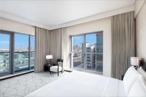 a bedroom with a large bed and large windows at Hyatt Place Dubai Jumeirah in Dubai