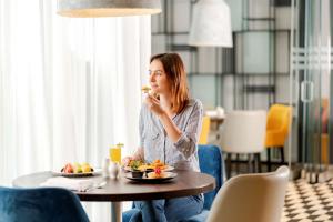 a woman sitting at a table eating food at Hyatt Place Dubai Jumeirah in Dubai