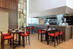 a restaurant with tables and red chairs and chefs in the kitchen at Hyatt Place Dubai Jumeirah in Dubai