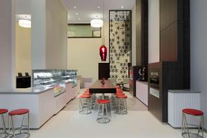 a kitchen with a table and some red stools at Hyatt Place Dubai Jumeirah in Dubai