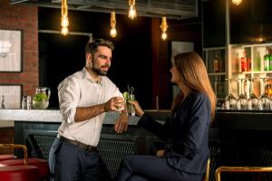 a man and a woman sitting at a bar holding a drink at Hyatt Place Dubai Jumeirah in Dubai