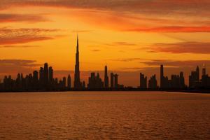 a city skyline at sunset with the tallest building at Hyatt Place Dubai Jumeirah in Dubai