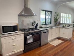 uma cozinha com um fogão e um micro-ondas em Cosy Queenslander in the heart of town. em Mareeba