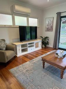 uma sala de estar com uma televisão de ecrã plano e uma mesa de centro em Cosy Queenslander in the heart of town. em Mareeba