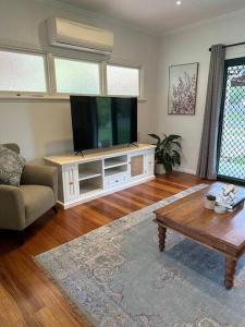 a living room with a flat screen tv and a coffee table at Cosy Queenslander in the heart of town. in Mareeba