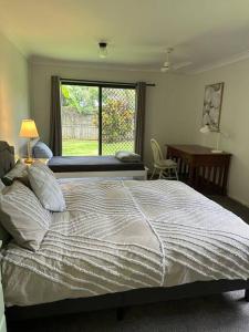 a bedroom with a bed and a desk and a window at Cosy Queenslander in the heart of town. in Mareeba