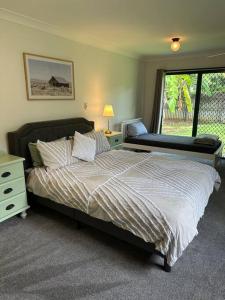 Un dormitorio con una cama grande y una ventana en Cosy Queenslander in the heart of town., en Mareeba