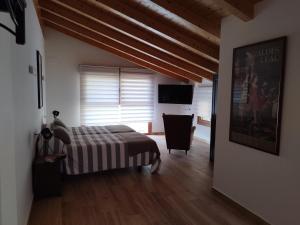 a bedroom with a bed and a chair and a television at Balcón del Aitzgorri in Mutiloa