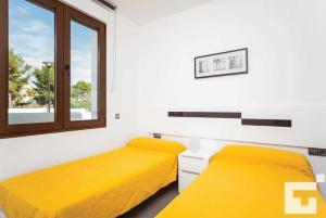 two beds in a room with yellow sheets and a window at Villa Mirador de Bassetes 4 - Grupo Turis in Calpe