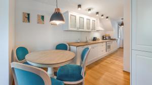 a kitchen with a table and blue chairs in a room at Apartamenty Sun & Snow Parkowa in Sopot