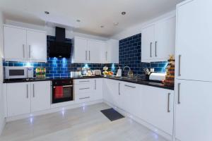 uma cozinha com armários brancos e uma parede de azulejos azuis em Nazarene apartments in Leeds em Stanningley