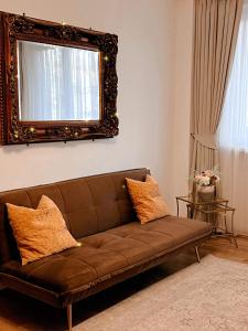 a brown couch in a living room with a mirror at Niran Apartament in Oradea