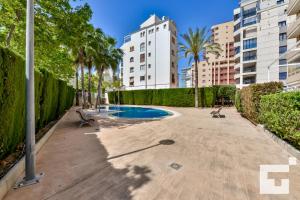 a swimming pool in a courtyard with trees and buildings at Apartamento Apolo XIX 34L - Grupo Turis in Calpe