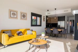 a living room with a yellow couch and a dining room at Villa Birdie Finestrat in Finestrat