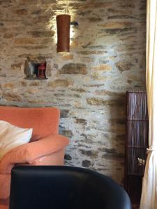 sala de estar con pared de piedra y sofá en CASA RURAL LA TI ISABEL, en Folgoso de la Carballeda