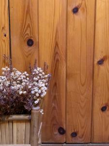 un jarrón de flores sentado junto a una pared de madera en CASA RURAL LA TI ISABEL, en Folgoso de la Carballeda