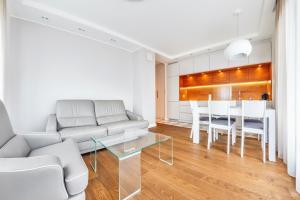 a living room with white furniture and a table at Aquarius, Sun & Snow in Sopot