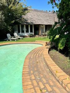 a dog sitting next to a brick walkway around a pool at Secured cottage in equestrian estate - LOADSHEDDING FREE! in Midrand