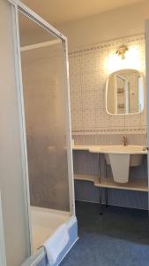 La salle de bains est pourvue d'une douche, d'un lavabo et d'un miroir. dans l'établissement Hotel Alicja, à Łódź