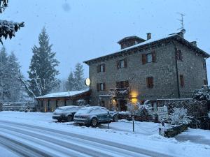 a large stone building with cars parked in the snow at Casa Benassi Room&breakfast in Riolunato