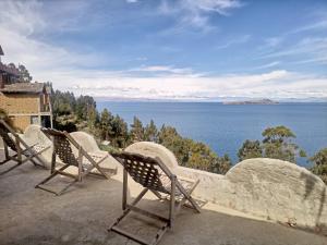 a row of chairs sitting on a ledge overlooking the ocean at Hostal Inca Uma in Comunidad Yumani