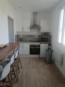 une cuisine avec des placards blancs et une table et des chaises en bois dans l'établissement Le Courlis, à deux minutes de la plage, à Hauteville-sur-Mer