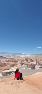 a person sitting on the sand in the desert at Alborada in San Fernando del Valle de Catamarca