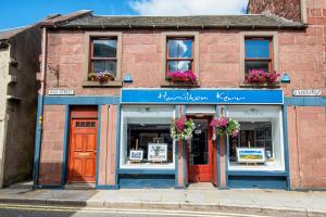 a brick building with flowers in the windows at Unique 2 Bedroom Flat Kirrie Scotland in Kirriemuir