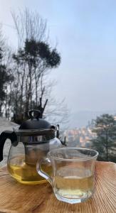 a tea pot and a glass cup on a table at Trippers hostel in Darjeeling