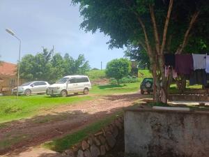 two cars parked on a dirt road next to a tree at Abid's Homestay in Kampala