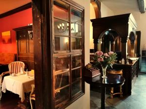 a room with a china cabinet and a table with flowers at Hotel Denkmal 13 Rostock - Kaufmannshaus Krahnstöver in Rostock