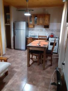 a kitchen with a table and a white refrigerator at Cabañas El Fogón in Potrerillos