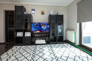 uma sala de estar com televisão e armários pretos em Apartament S46 em Roman